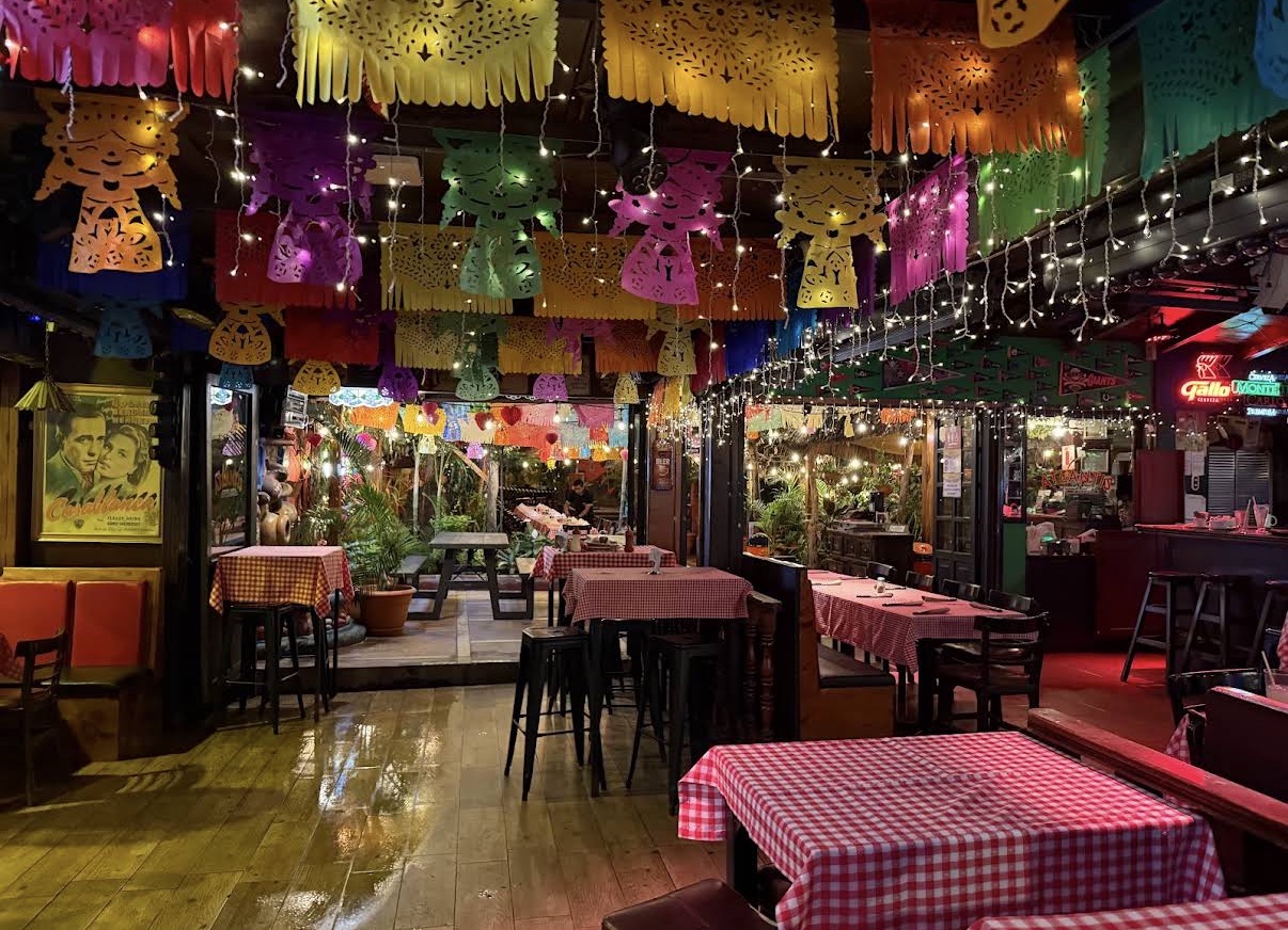 Interior de Lena's Atlantis decorado con papel picado colorido y mesas con manteles a cuadros